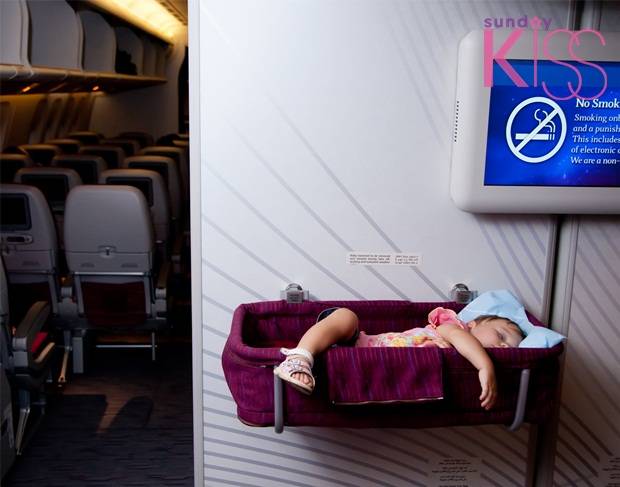 Travel with children. Small two year old baby girl sleep in a special bassinet on a airplane