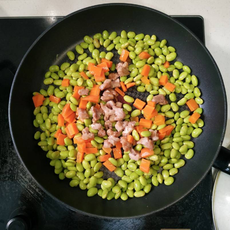 家常菜 中火下油起鑊，倒入毛豆，紅蘿蔔及肉粒炒2分鐘。
