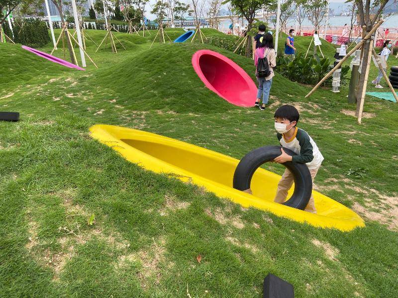 海濱長廊 設置了一個以「童樂園」為主題的活動區，藉着園境設計、高低起伏的草坪，配以色彩鮮艷的渠桶，於鬧市中營造天然風格的自由活動空間。