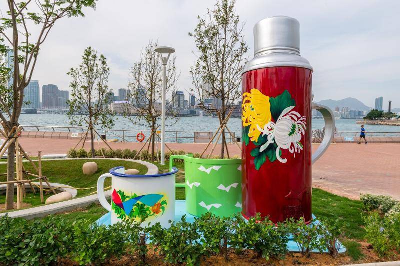 海濱長廊 新開放草坪上的藝術裝置「奉茶•問暖」，把富有香港特色的舊式暖水壺和水杯放大，讓市民在海濱感受身在家中客廳的感覺。