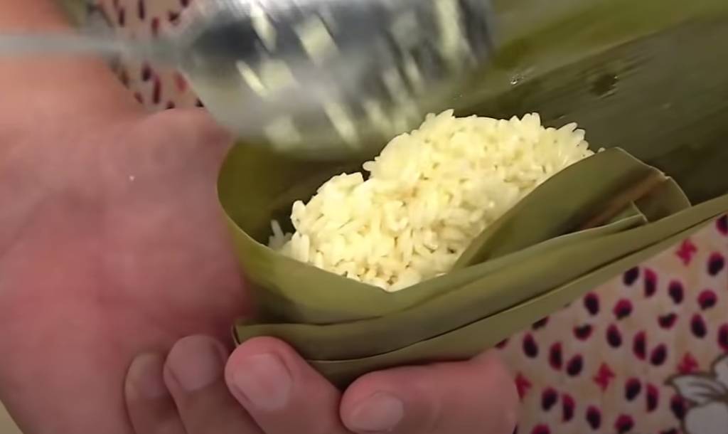 粽子做法 先放半份糯米在葉中，藏入蘇木，蓋上半份糯米，再放上一片竹葉。
