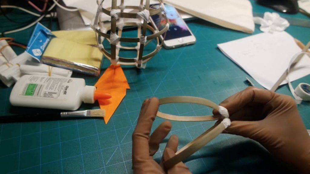 燈籠DIY 4. 其後製作兔子頭，先裁出兩條10cm的竹篾，屈曲至水滴形。在竹篾尖端的位置貼上紙膠帶，把兩個水滴形的竹篾連接。在竹篾後面位置貼上6cm竹篾。
