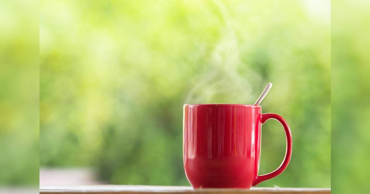 消滯方法 消滯茶 Red coffee mug on wooden tabletop against grunge green blur background